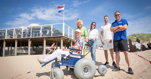 Foto groepje mensen bij strandrolstoel